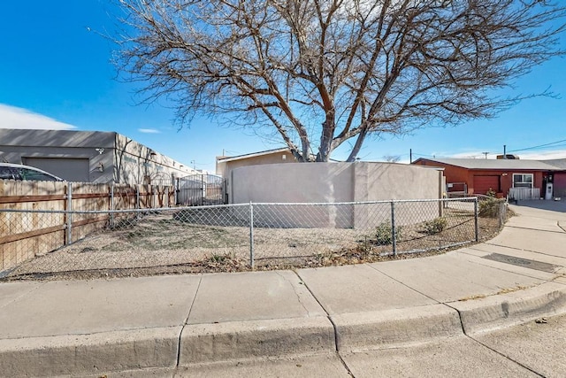 view of property exterior featuring a fenced front yard, concrete driveway, a garage, and stucco siding