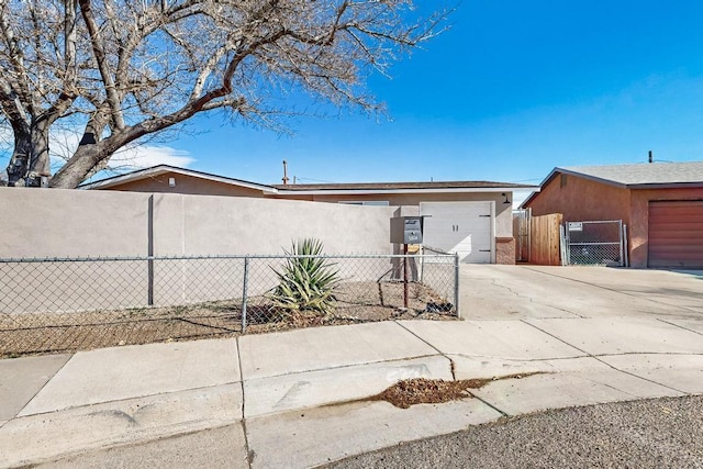 view of home's exterior with concrete driveway, a fenced front yard, an attached garage, a gate, and stucco siding