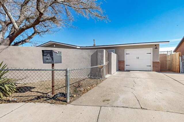 view of side of property featuring an attached garage, brick siding, fence, driveway, and stucco siding