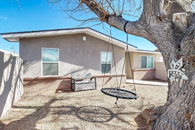 back of property featuring brick siding, fence, and stucco siding