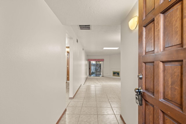 hallway featuring light tile patterned floors and a textured ceiling