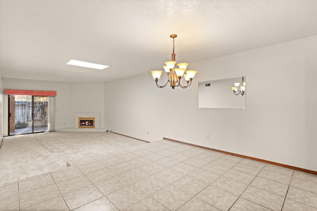 unfurnished living room with a fireplace, a chandelier, and a textured ceiling