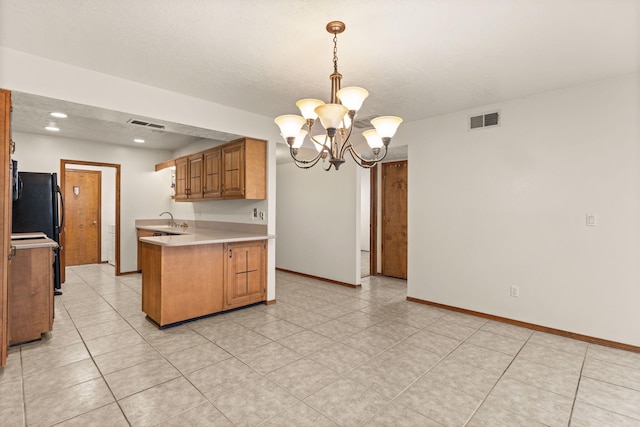 kitchen with sink, hanging light fixtures, black refrigerator, kitchen peninsula, and a notable chandelier