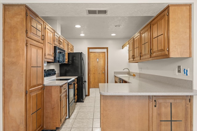 kitchen featuring kitchen peninsula, light tile patterned floors, a textured ceiling, and black appliances