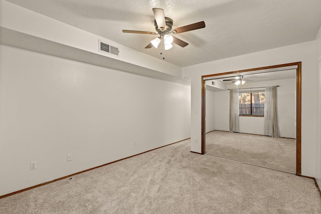 carpeted empty room with ceiling fan and a textured ceiling