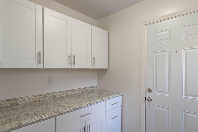 interior space with light stone countertops and white cabinets