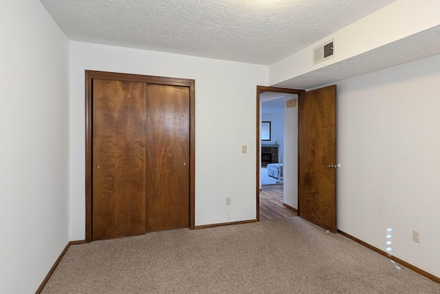 unfurnished bedroom with carpet floors, a closet, and a textured ceiling