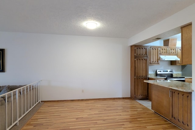 kitchen featuring electric stove, light hardwood / wood-style flooring, and a textured ceiling