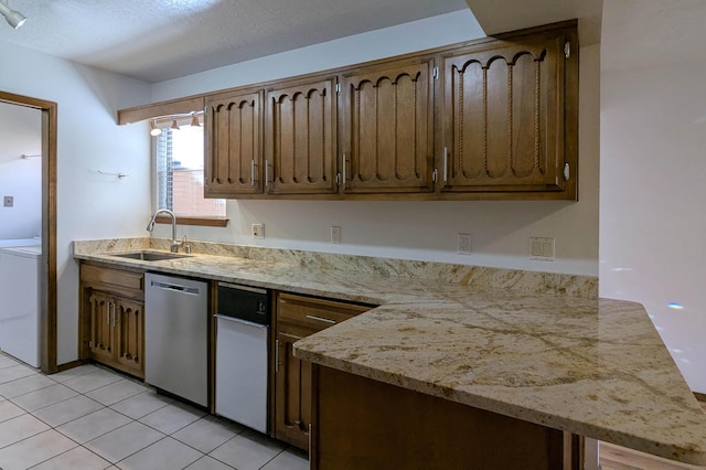 kitchen with washer / clothes dryer, dishwasher, sink, light tile patterned floors, and light stone countertops