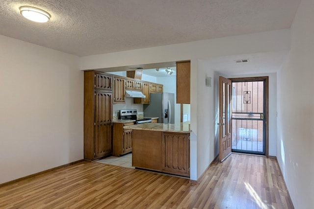 kitchen with stainless steel appliances, light hardwood / wood-style flooring, and a textured ceiling