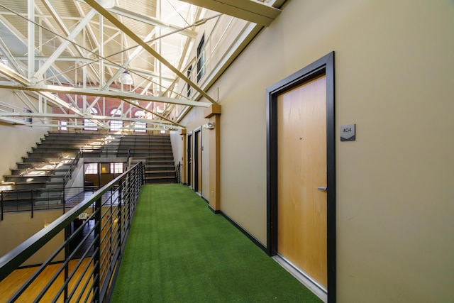 hallway featuring a towering ceiling and carpet floors