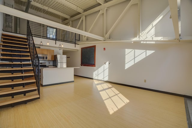 unfurnished living room featuring light hardwood / wood-style flooring, plenty of natural light, and high vaulted ceiling