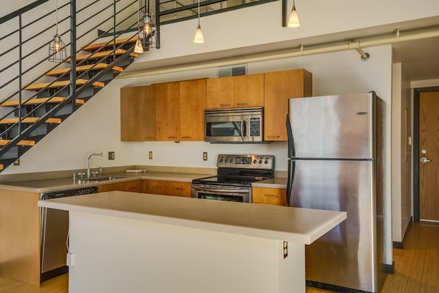 kitchen featuring sink, a center island, pendant lighting, stainless steel appliances, and a high ceiling