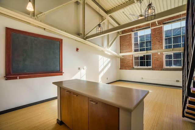 kitchen featuring beam ceiling, decorative light fixtures, high vaulted ceiling, and light hardwood / wood-style flooring