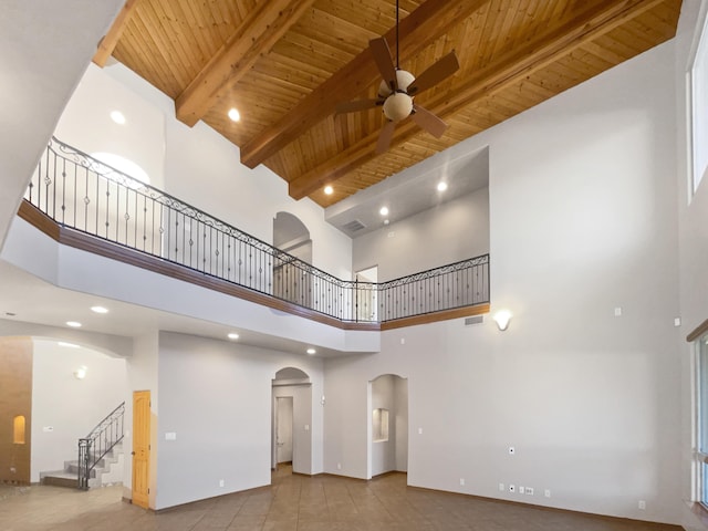 living room with wood ceiling, ceiling fan, beam ceiling, and a high ceiling