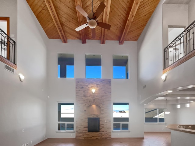 unfurnished living room featuring beamed ceiling, wooden ceiling, and a fireplace