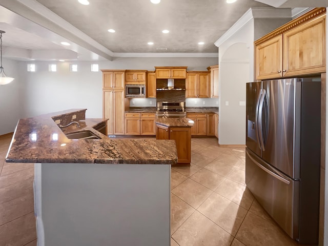 kitchen featuring pendant lighting, sink, wall chimney range hood, appliances with stainless steel finishes, and a kitchen island with sink