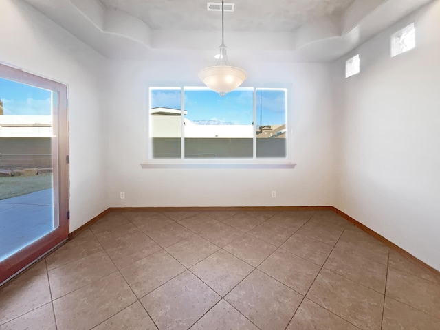 tiled empty room featuring a tray ceiling