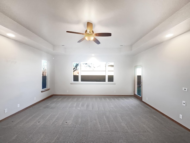 spare room with ceiling fan, carpet flooring, and a tray ceiling