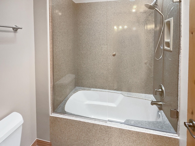 bathroom featuring tiled shower / bath combo and toilet