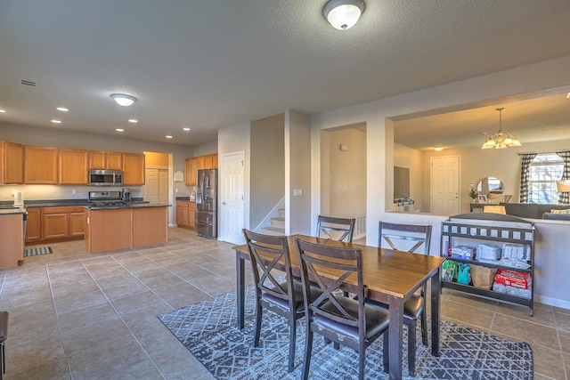 dining area featuring a notable chandelier, light tile patterned floors, and a textured ceiling