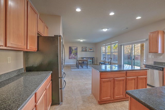 kitchen featuring stainless steel appliances, dark stone counters, a kitchen island, and light tile patterned floors