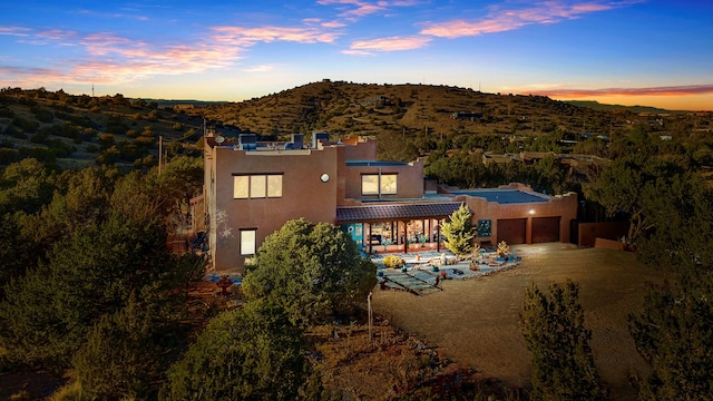 back house at dusk with a garage and a mountain view