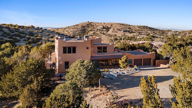 29 Sandia Ln, Placitas, NM 87043 - view of front facade featuring a garage, gravel driveway, stucco siding, and a mountain view