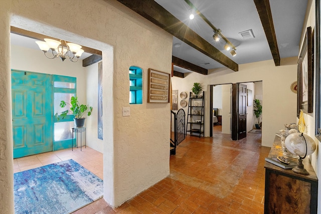 29 Sandia Ln, Placitas, NM 87043 - entrance foyer with a textured wall, visible vents, beamed ceiling, brick floor, and a chandelier