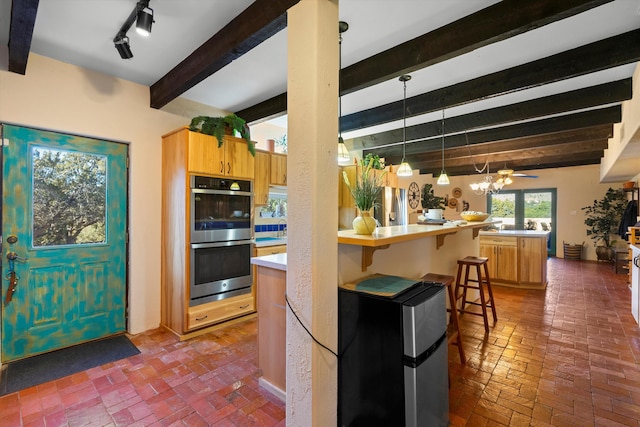 kitchen featuring a breakfast bar, hanging light fixtures, appliances with stainless steel finishes, kitchen peninsula, and beam ceiling