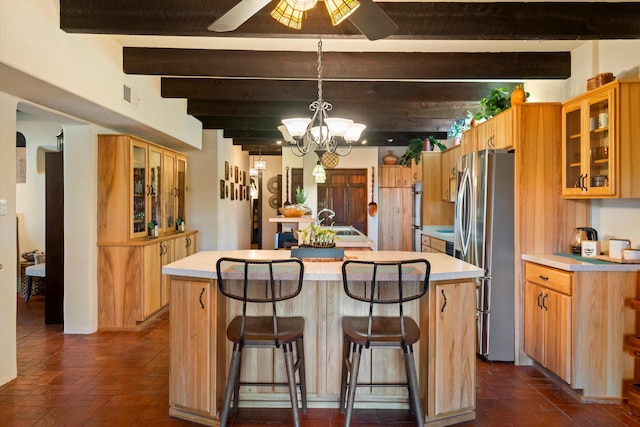 kitchen with a kitchen bar, a center island, hanging light fixtures, stainless steel refrigerator, and beamed ceiling