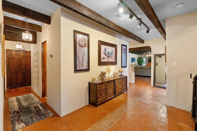 hall featuring rail lighting and beamed ceiling