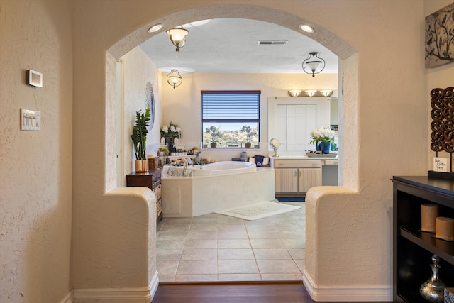 29 Sandia Ln, Placitas, NM 87043 - full bath featuring a garden tub, wood finished floors, vanity, a textured wall, and visible vents