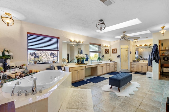 bathroom with tile patterned flooring, a skylight, vanity, a textured ceiling, and separate shower and tub