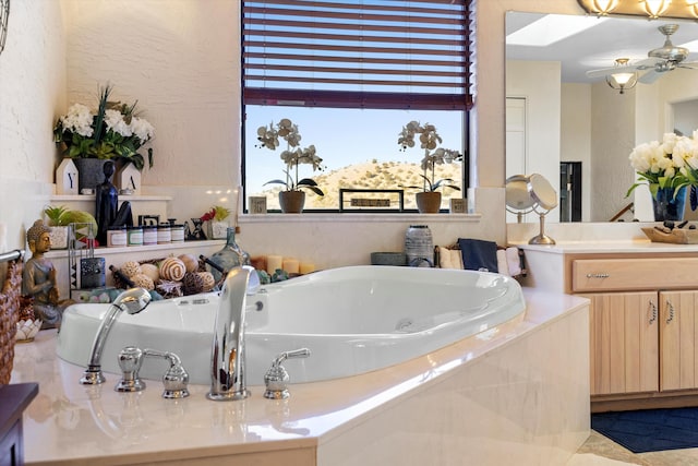 bathroom with ceiling fan, vanity, and tiled bath