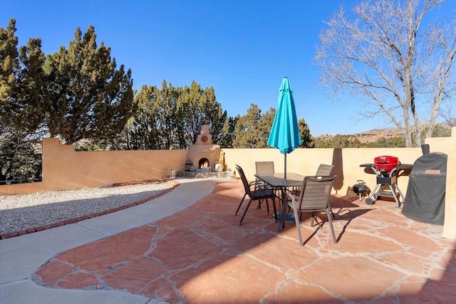 29 Sandia Ln, Placitas, NM 87043 - view of patio / terrace featuring fence, a lit fireplace, and outdoor dining space