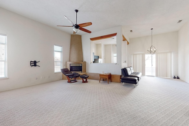 sitting room with ceiling fan with notable chandelier, carpet floors, and a textured ceiling