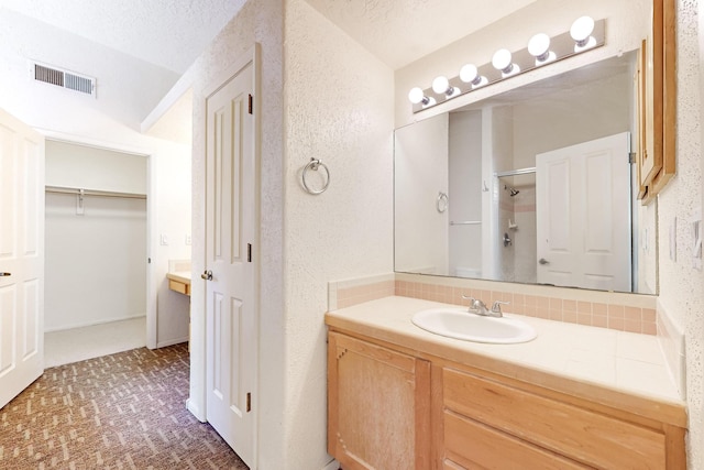 bathroom featuring vanity, a textured ceiling, and walk in shower