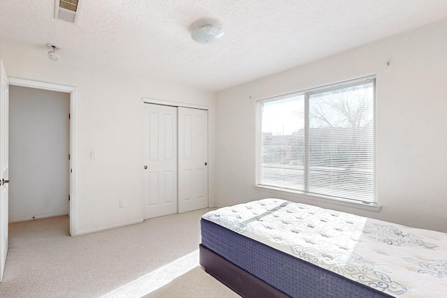 bedroom with carpet, a textured ceiling, and a closet