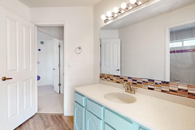 bathroom featuring hardwood / wood-style flooring, vanity, a shower, and decorative backsplash