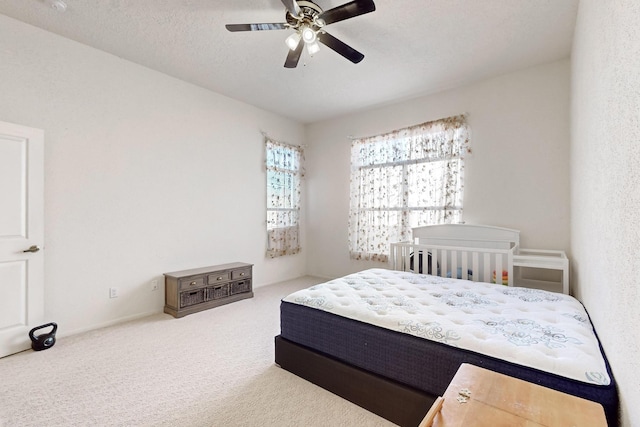 carpeted bedroom featuring ceiling fan and a textured ceiling