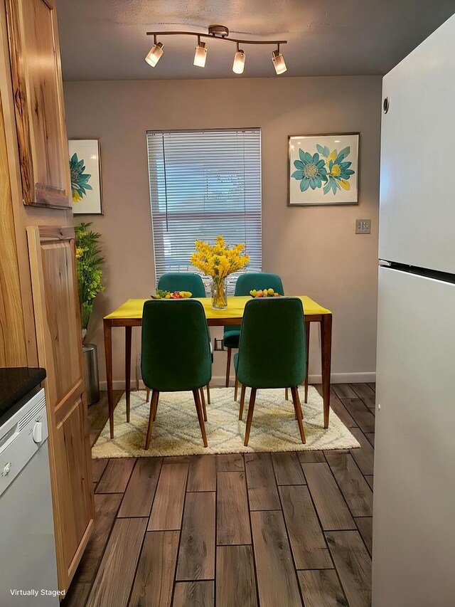 dining space with dark hardwood / wood-style flooring and rail lighting