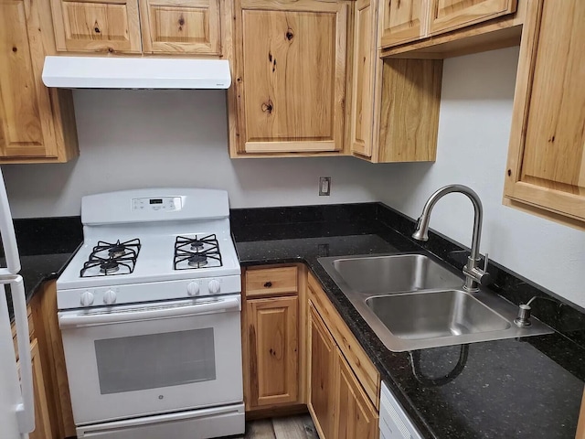 kitchen with sink, ventilation hood, dark stone counters, and white gas stove