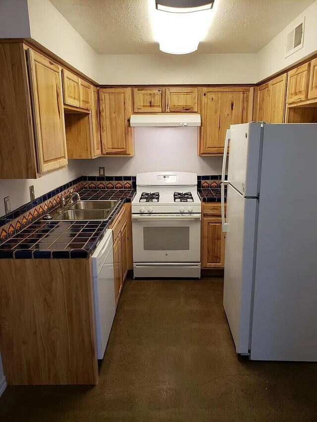 kitchen featuring white appliances, tile countertops, sink, and a textured ceiling