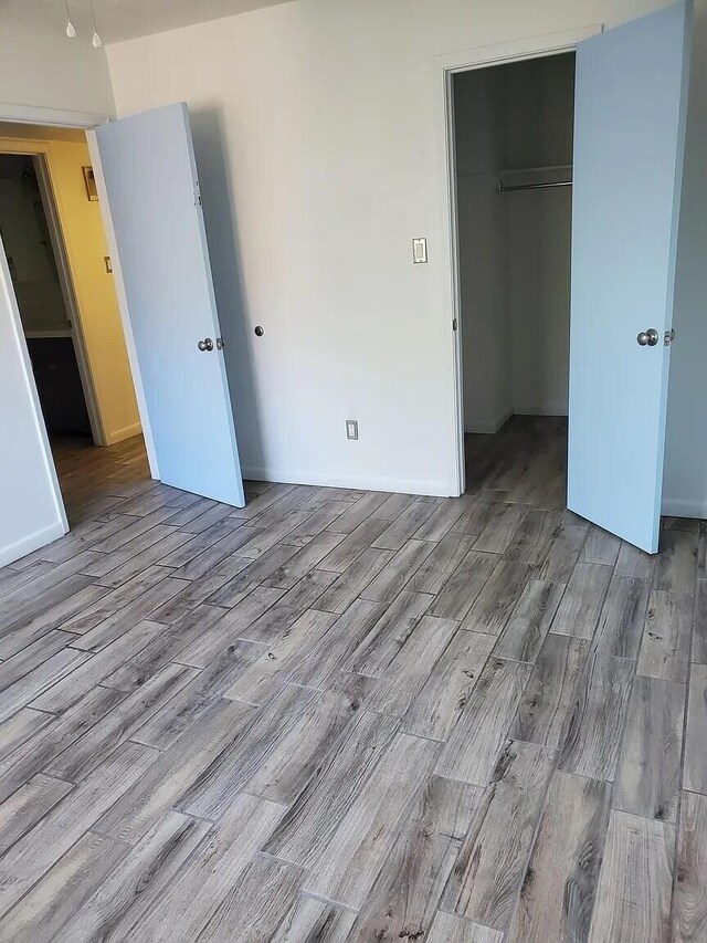 unfurnished bedroom featuring a walk in closet, light hardwood / wood-style floors, and a closet