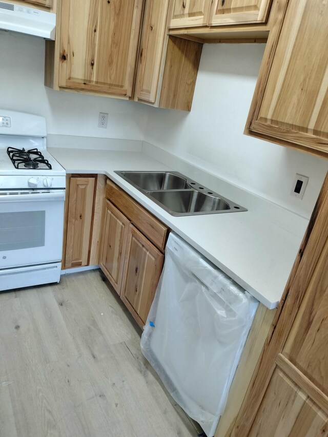 kitchen featuring white appliances, light hardwood / wood-style floors, and sink