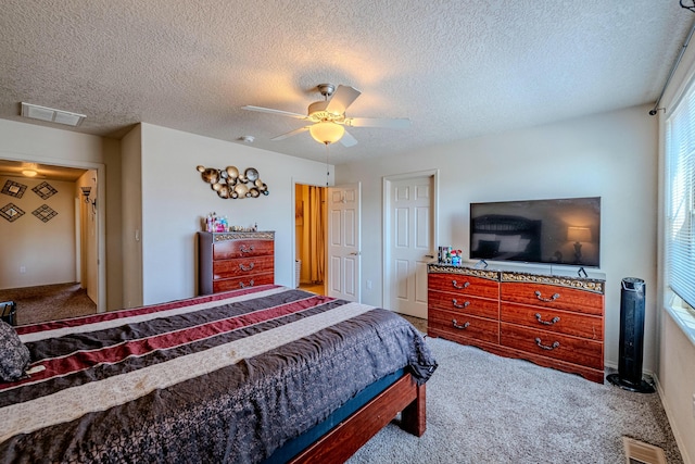 bedroom with ceiling fan, carpet, and a textured ceiling