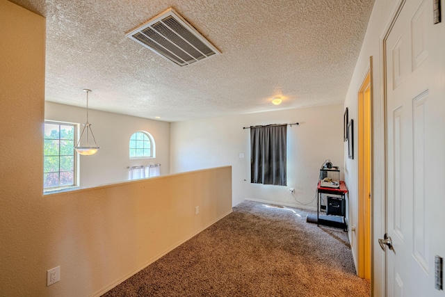 corridor featuring a textured ceiling and carpet