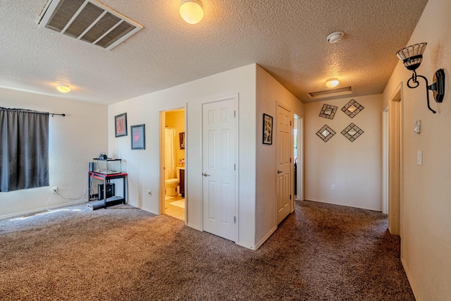 hallway featuring a textured ceiling and dark carpet