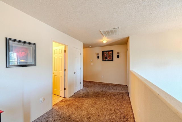 hall featuring light colored carpet and a textured ceiling